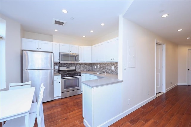 kitchen featuring dark hardwood / wood-style floors, white cabinetry, backsplash, and appliances with stainless steel finishes