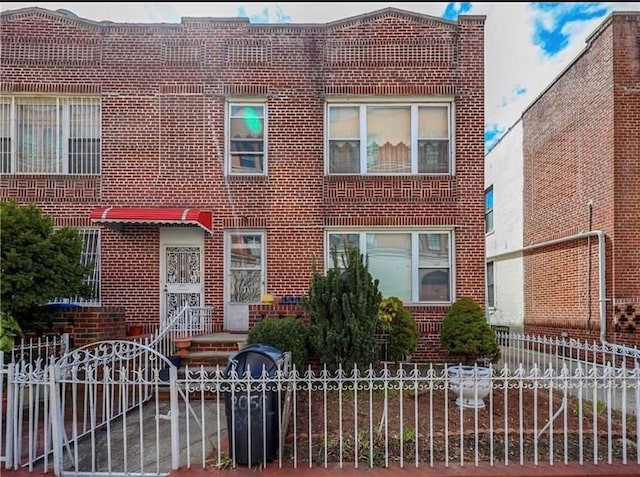 view of front facade featuring brick siding and a fenced front yard