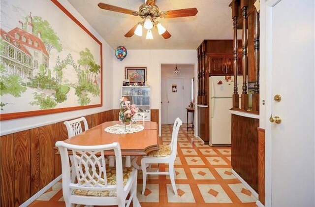 dining room featuring ceiling fan and wood walls