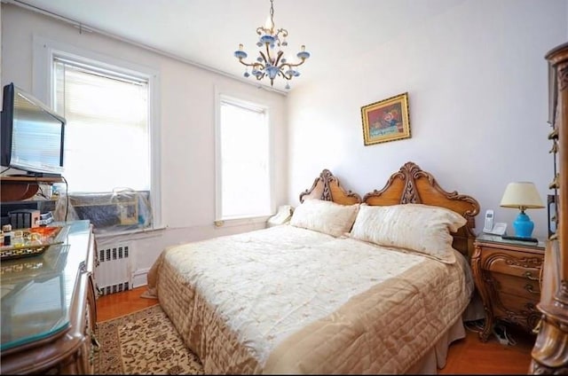 bedroom featuring radiator heating unit, a chandelier, and wood finished floors