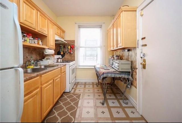 kitchen featuring tasteful backsplash, light brown cabinetry, sink, and white appliances