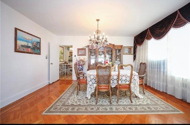 dining room featuring a chandelier and parquet flooring