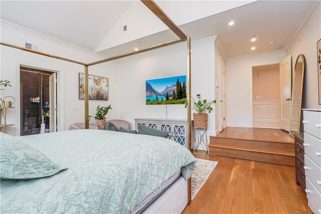 bedroom featuring light hardwood / wood-style floors, lofted ceiling, and ornamental molding