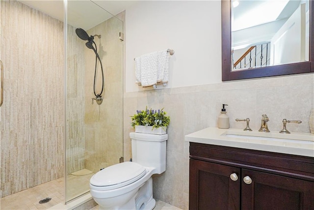 bathroom featuring vanity, a wainscoted wall, a tile shower, tile walls, and toilet