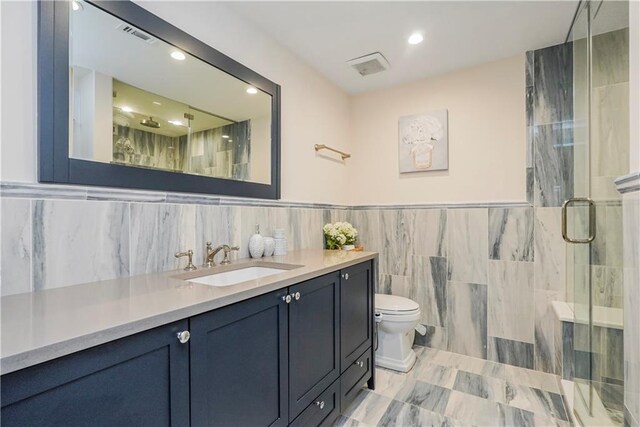 bathroom with vanity, an enclosed shower, tile walls, and toilet