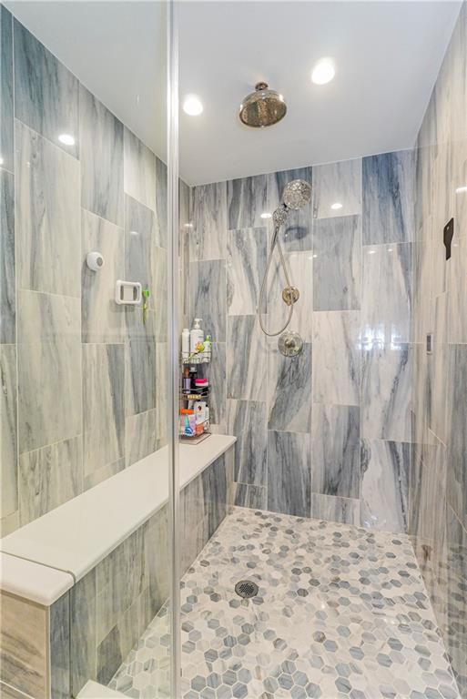 bathroom featuring tiled shower and tile walls