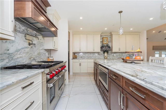 kitchen featuring marble finish floor, custom range hood, appliances with stainless steel finishes, light stone countertops, and hanging light fixtures