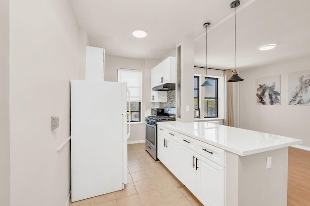 kitchen with stainless steel gas stove, white cabinetry, decorative backsplash, hanging light fixtures, and white fridge