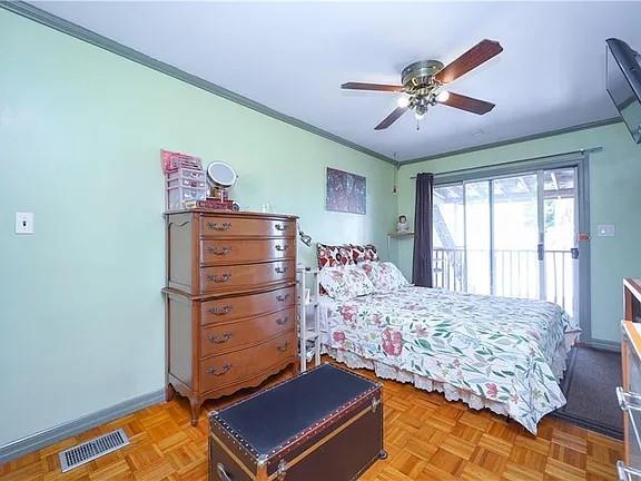 bedroom featuring light parquet floors, ornamental molding, and ceiling fan