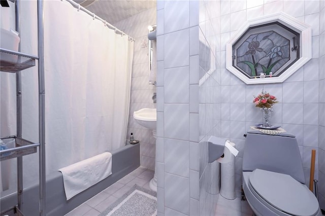 bathroom with tile patterned floors, toilet, tile walls, and shower / tub combo