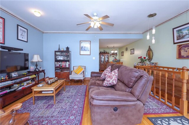 living room featuring ceiling fan with notable chandelier, light hardwood / wood-style flooring, and crown molding