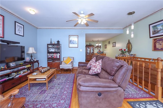 living room with crown molding, ceiling fan with notable chandelier, and light wood-type flooring