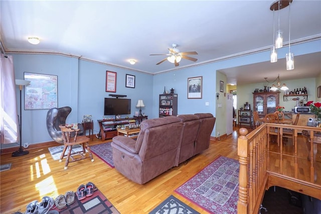 living area featuring baseboards, crown molding, a ceiling fan, and wood finished floors