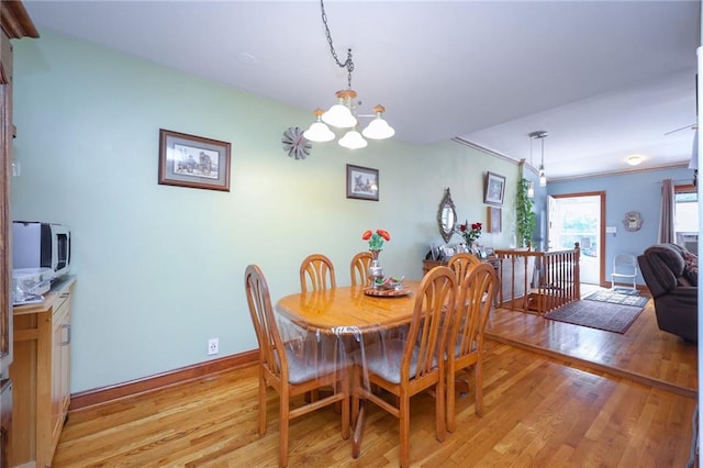 dining room featuring light wood-style flooring, a notable chandelier, and baseboards