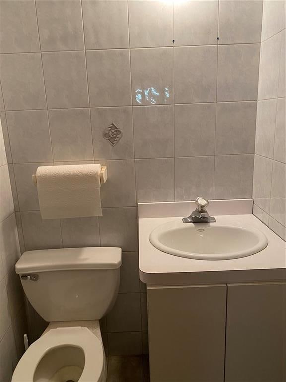 bathroom with vanity, toilet, and tile walls