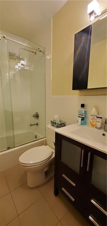 full bathroom featuring tile patterned flooring, vanity, toilet, and bath / shower combo with glass door