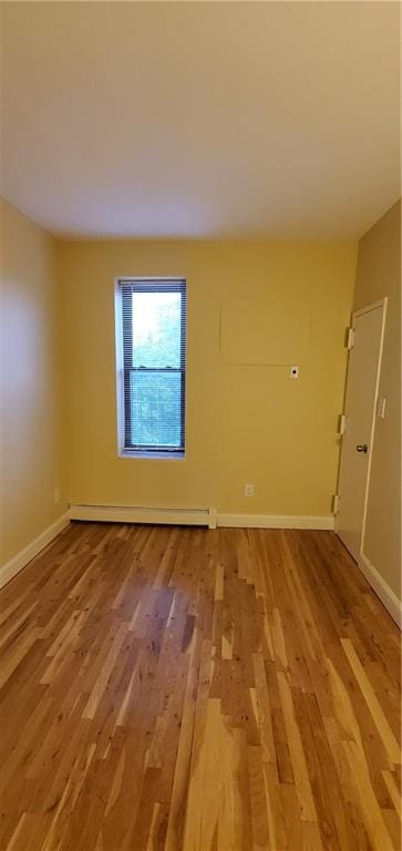 spare room with hardwood / wood-style floors and a baseboard heating unit