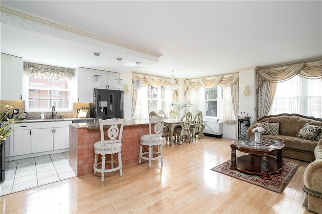 kitchen with a center island, open floor plan, light wood-type flooring, a kitchen bar, and black fridge