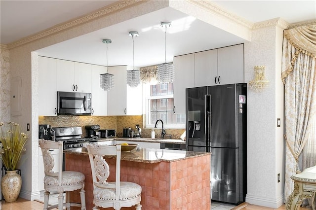 kitchen with wallpapered walls, stone counters, stainless steel appliances, and a breakfast bar area