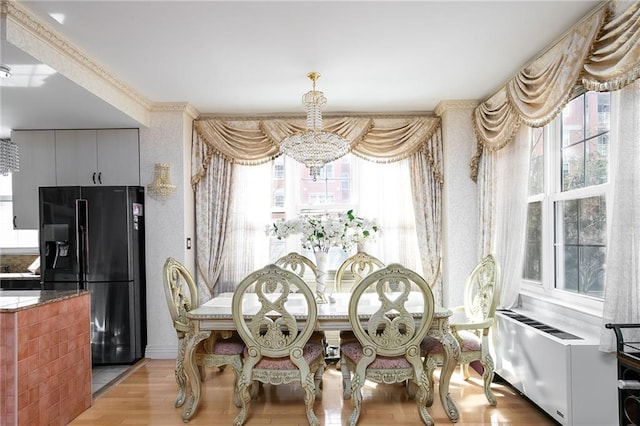 dining area featuring light wood-style floors, radiator heating unit, and an inviting chandelier