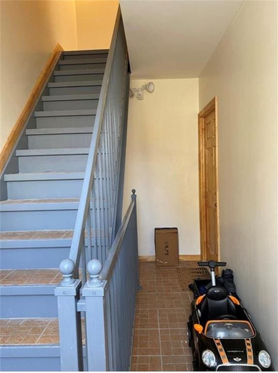 staircase featuring brick patterned floor