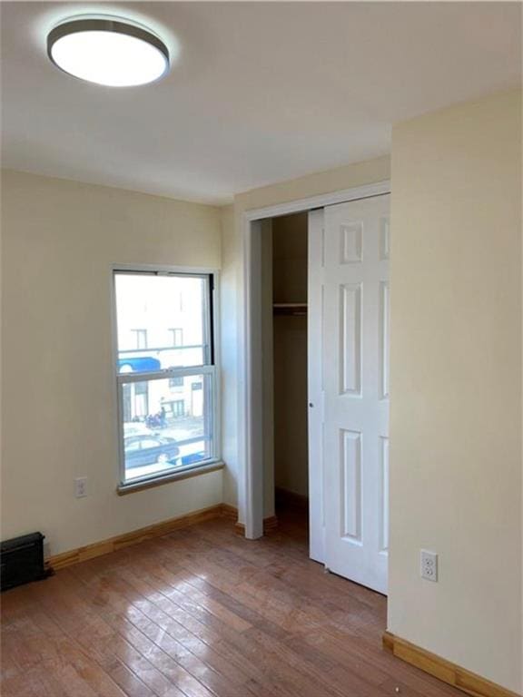 unfurnished bedroom with light wood-style floors, baseboards, and a closet