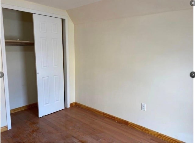 unfurnished bedroom featuring a closet, dark hardwood / wood-style flooring, and vaulted ceiling