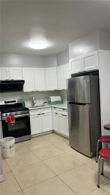 kitchen featuring white cabinets, light tile patterned flooring, sink, ventilation hood, and appliances with stainless steel finishes