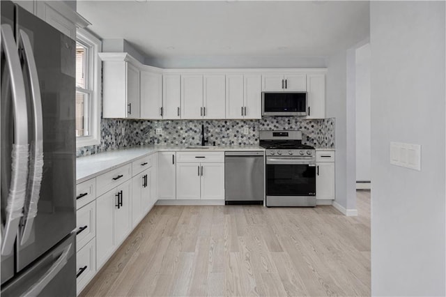 kitchen featuring appliances with stainless steel finishes, light hardwood / wood-style floors, white cabinetry, and sink