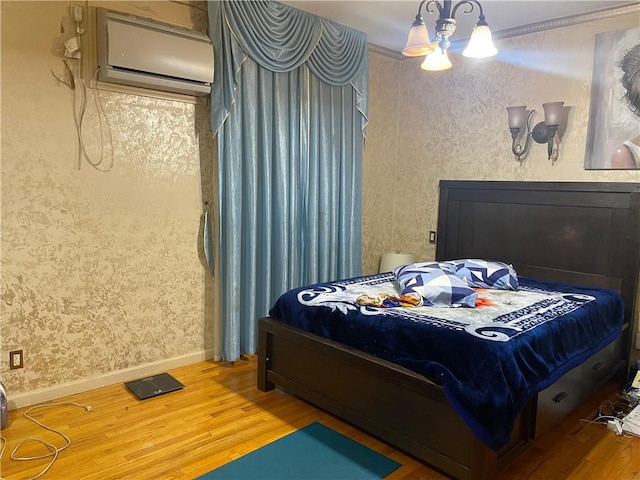 bedroom featuring wood-type flooring, an inviting chandelier, a wall mounted air conditioner, and ornamental molding