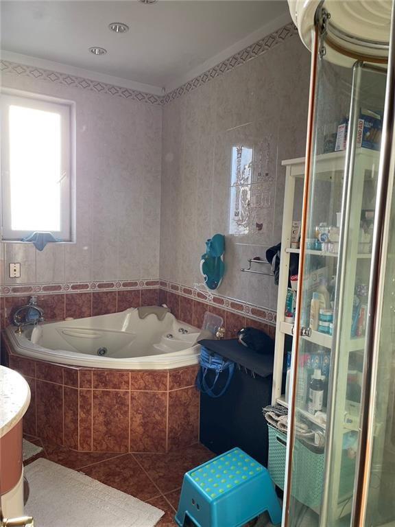 bathroom with tile patterned flooring, tiled bath, and crown molding