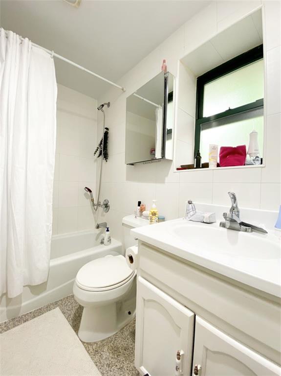 full bathroom with vanity, tile walls, shower / tub combo with curtain, toilet, and decorative backsplash