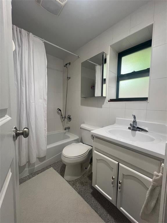 full bathroom with tile walls, vanity, toilet, and shower / bathtub combination with curtain