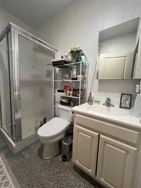 bathroom with vanity, tile walls, toilet, and an enclosed shower