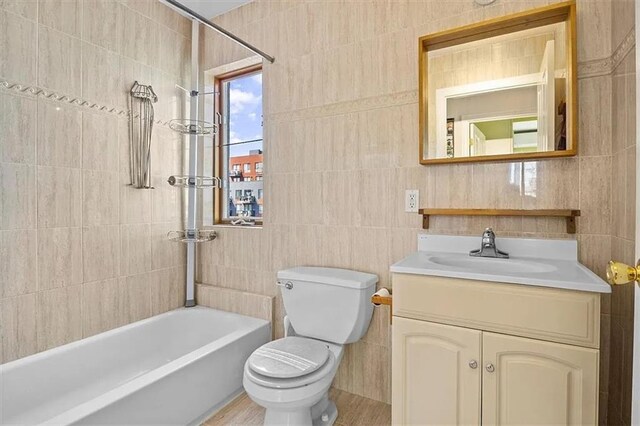 full bathroom featuring vanity, toilet, tile walls, and bathtub / shower combination