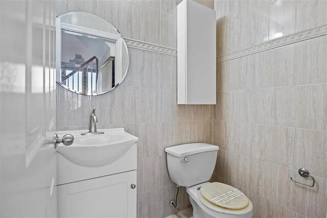 bathroom featuring vanity, toilet, and tile walls