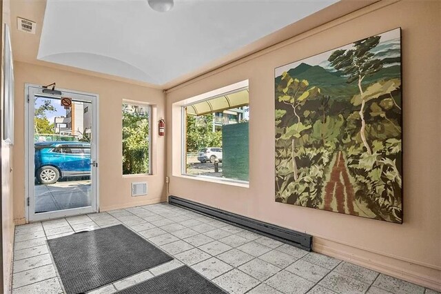 unfurnished sunroom with lofted ceiling and a baseboard heating unit