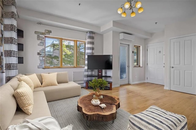 living room with an inviting chandelier, light hardwood / wood-style flooring, a baseboard heating unit, and a wall mounted AC