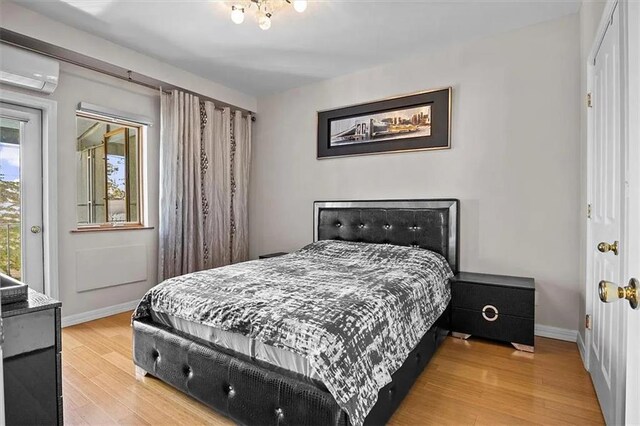 bedroom with light wood-type flooring and a wall mounted AC