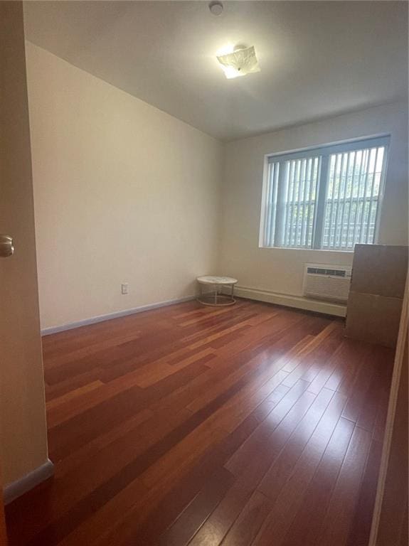 empty room with a wall mounted air conditioner and dark hardwood / wood-style flooring