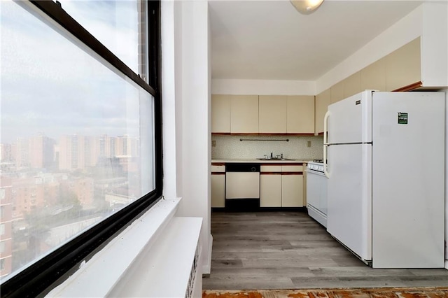 kitchen with light wood-type flooring, a sink, cream cabinets, backsplash, and white appliances