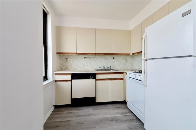 kitchen with a sink, backsplash, cream cabinets, white appliances, and light countertops