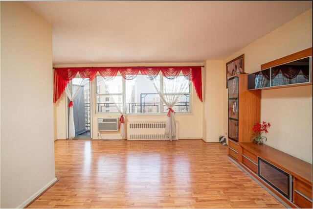 living room with radiator heating unit, a wall unit AC, and wood-type flooring