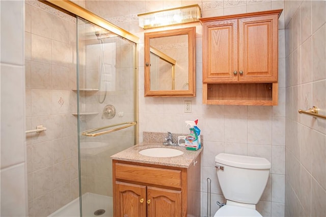 bathroom with vanity, tile walls, an enclosed shower, and toilet