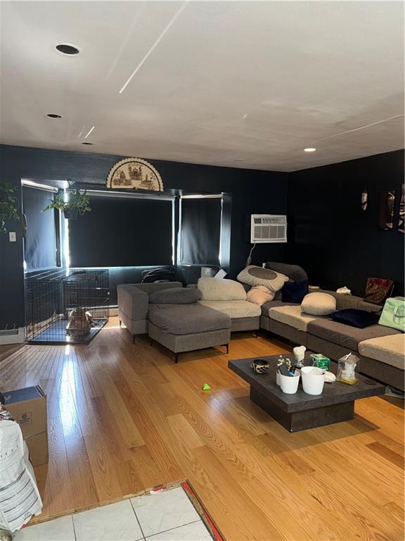 living room with light hardwood / wood-style flooring and a wall unit AC