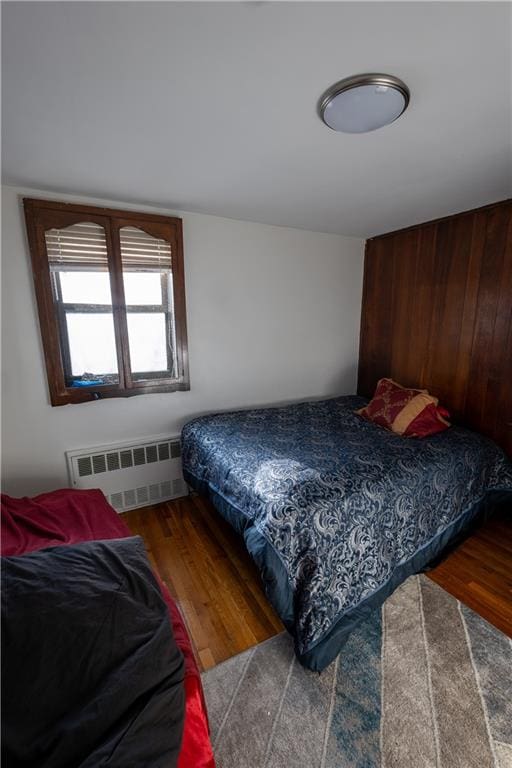 bedroom featuring radiator heating unit and wood finished floors