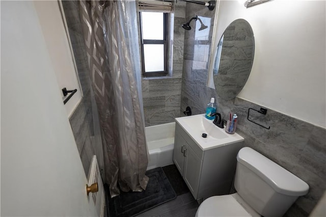 bathroom with tile walls, shower / tub combo with curtain, toilet, and vanity