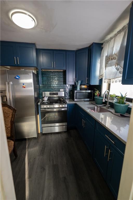 kitchen featuring tasteful backsplash, a sink, stainless steel appliances, blue cabinets, and dark wood-style flooring