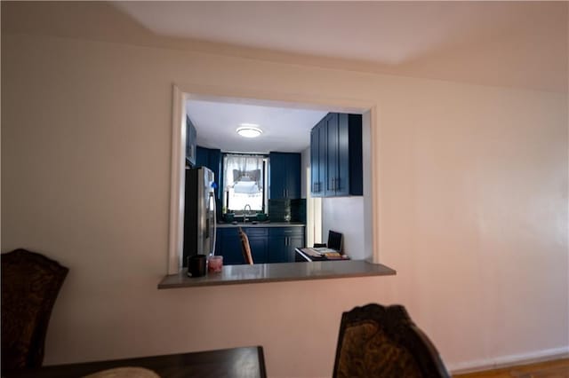 kitchen with freestanding refrigerator, blue cabinets, and a sink