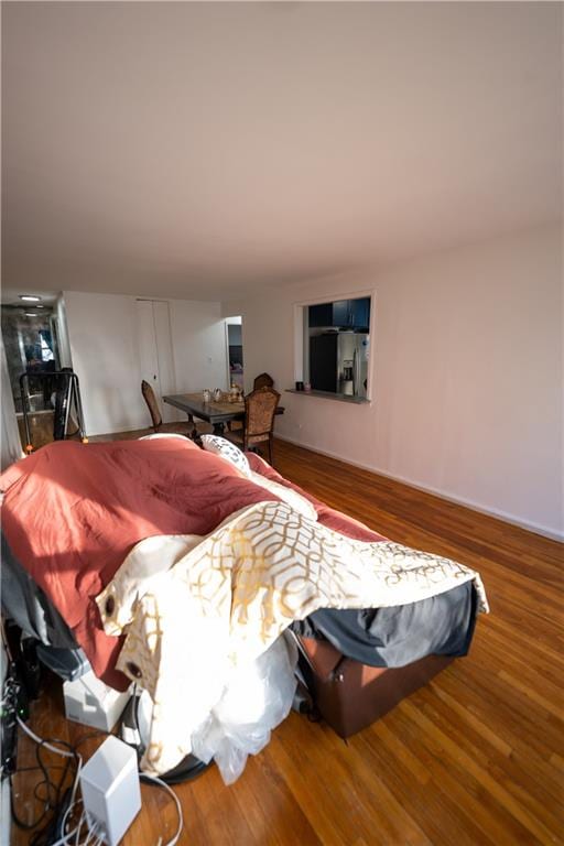 bedroom featuring stainless steel fridge with ice dispenser and wood finished floors